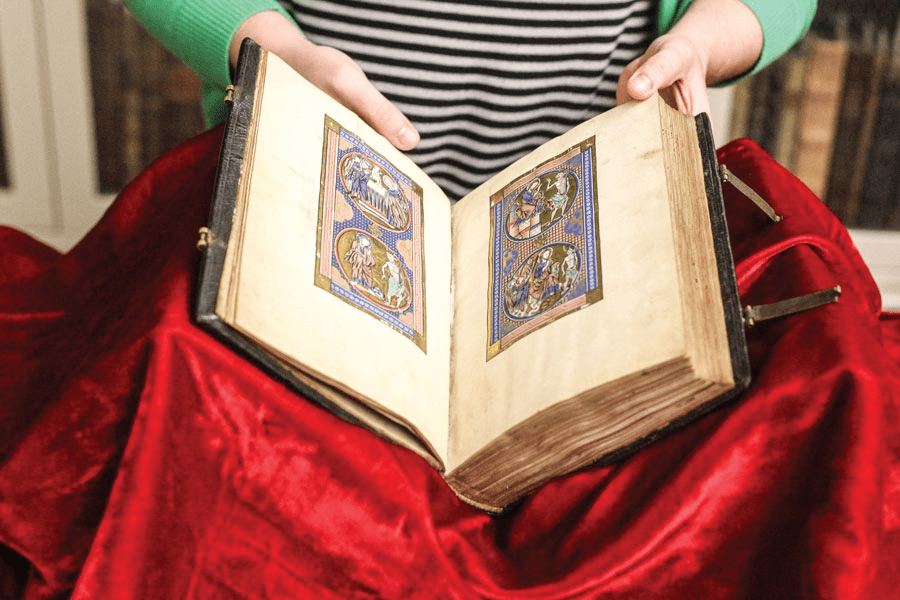 A collection of old, rare books with ornate covers on display.